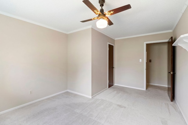 empty room featuring light colored carpet, ornamental molding, a ceiling fan, and baseboards