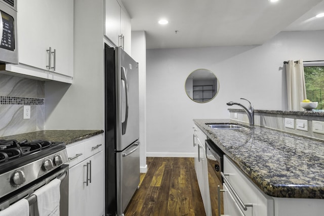 kitchen featuring sink, white cabinetry, appliances with stainless steel finishes, dark hardwood / wood-style flooring, and dark stone counters