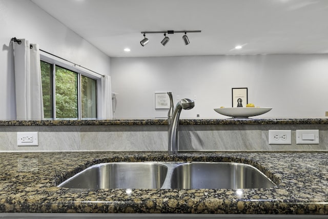 kitchen featuring rail lighting, sink, and dark stone counters