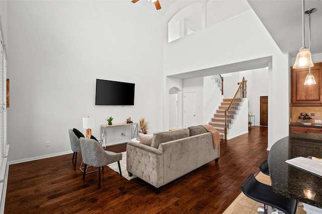 living room featuring dark hardwood / wood-style floors, ceiling fan, and a high ceiling