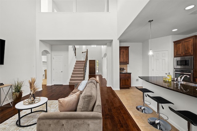 living room featuring sink, light hardwood / wood-style flooring, and a high ceiling