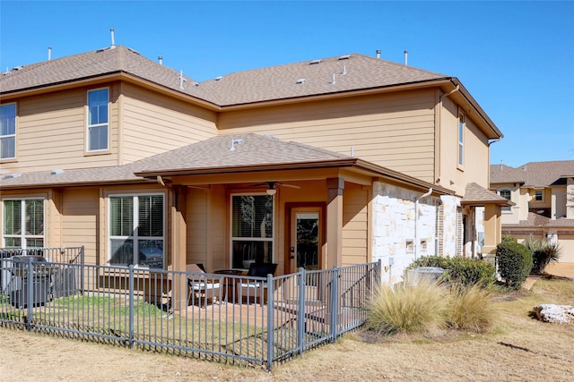 rear view of property with a lawn and ceiling fan