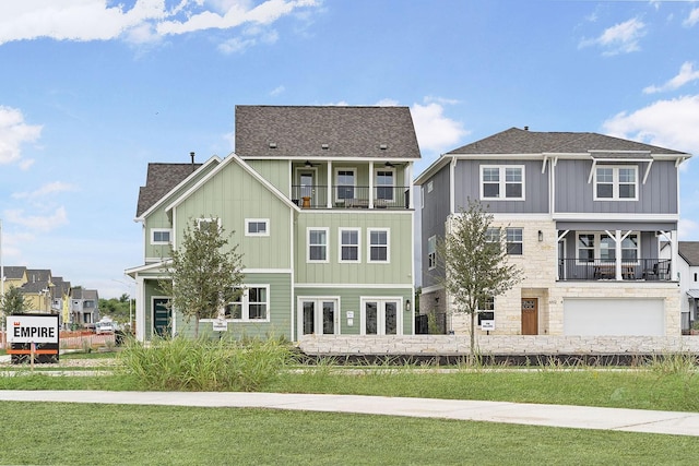 rear view of house with a balcony, a garage, and a lawn