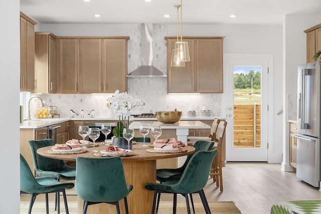 kitchen featuring wall chimney exhaust hood, a center island, hanging light fixtures, high quality fridge, and backsplash