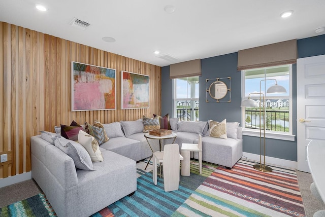 carpeted living room featuring wooden walls