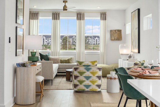 living area with wood-type flooring and ceiling fan