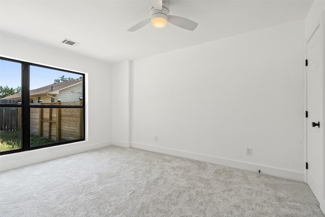 carpeted empty room with a wealth of natural light and ceiling fan