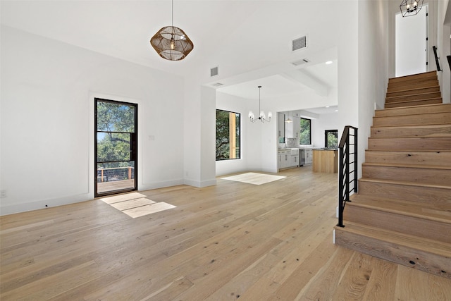 unfurnished living room with an inviting chandelier and light hardwood / wood-style floors