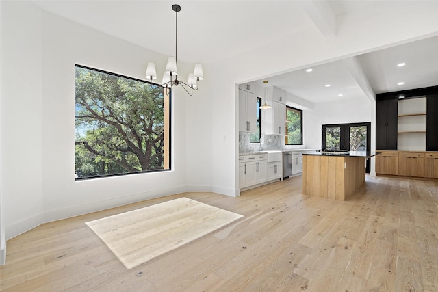 kitchen featuring decorative light fixtures, white cabinets, backsplash, a center island, and stainless steel dishwasher