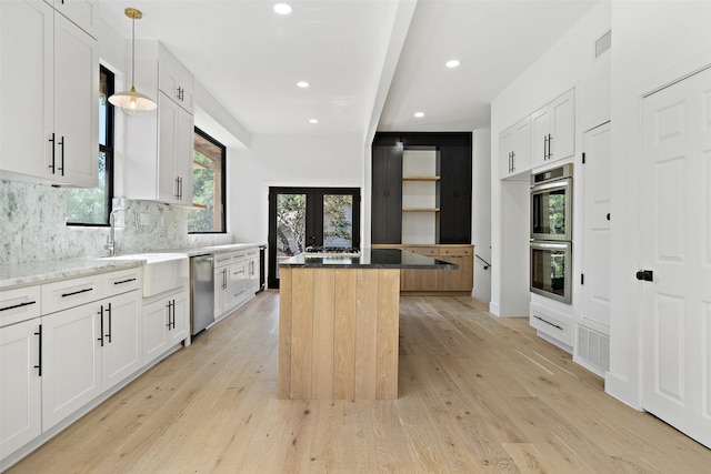 kitchen featuring light hardwood / wood-style flooring, hanging light fixtures, stainless steel appliances, a center island, and white cabinets