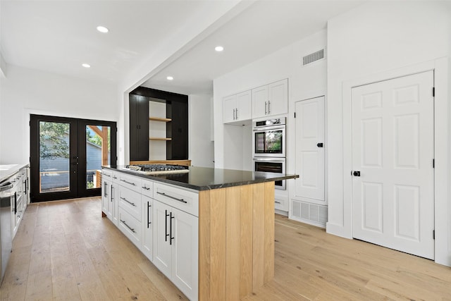 kitchen featuring white cabinetry, stainless steel appliances, a center island, light hardwood / wood-style floors, and french doors