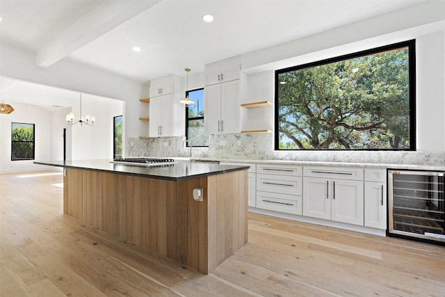 kitchen featuring beverage cooler, a center island, beam ceiling, and white cabinets