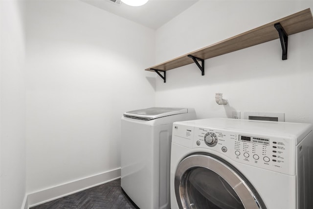 clothes washing area featuring washing machine and clothes dryer and dark parquet floors