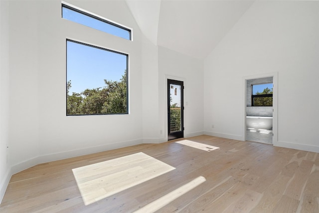 unfurnished room featuring a towering ceiling and light hardwood / wood-style flooring