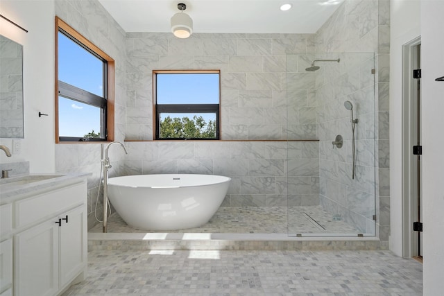 bathroom with independent shower and bath, vanity, and tile walls