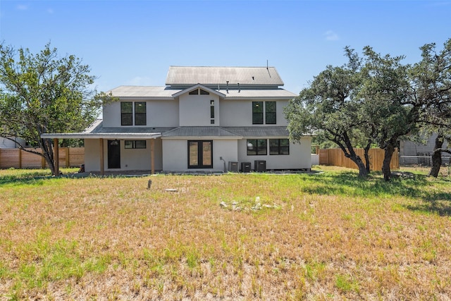 back of house featuring central AC unit and a lawn