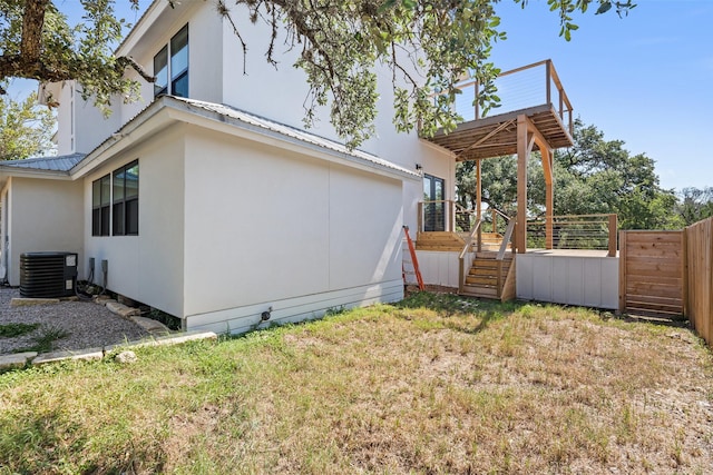 view of side of home with a wooden deck, central AC, and a lawn