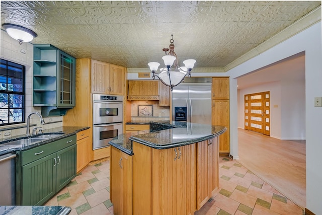 kitchen featuring sink, appliances with stainless steel finishes, hanging light fixtures, a kitchen island, and dark stone counters