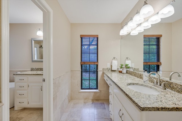 bathroom featuring tile patterned flooring, vanity, a wealth of natural light, and tile walls