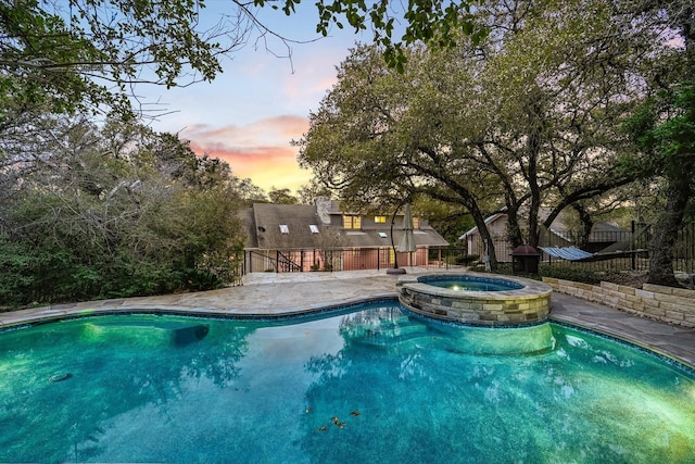 pool at dusk with an in ground hot tub