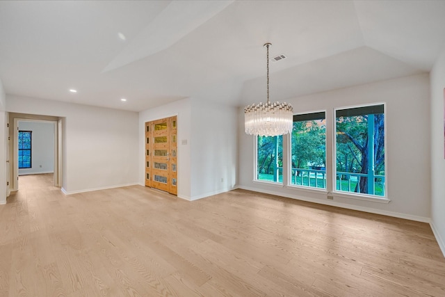 empty room with a notable chandelier, vaulted ceiling, and light wood-type flooring