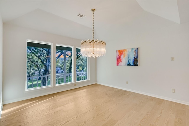 empty room with hardwood / wood-style flooring, vaulted ceiling, and an inviting chandelier