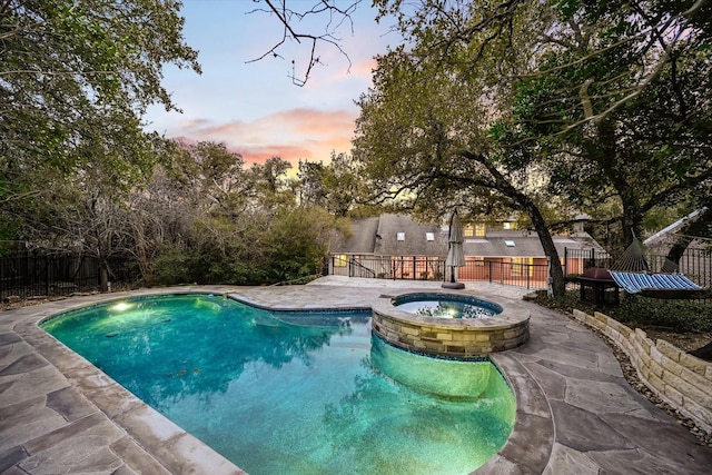 pool at dusk with an in ground hot tub