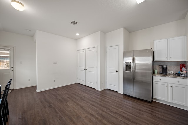 kitchen with stainless steel fridge, light stone countertops, decorative backsplash, and white cabinets