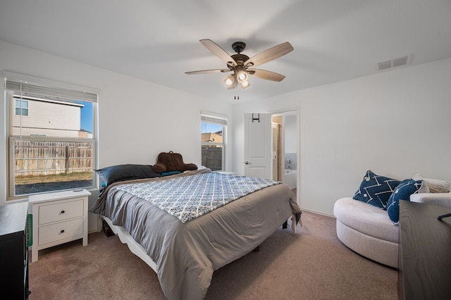 carpeted bedroom with ensuite bathroom and ceiling fan