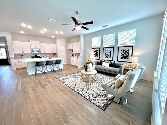 living room with light hardwood / wood-style floors and ceiling fan