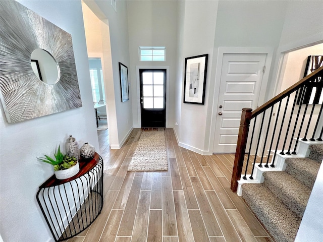 entrance foyer featuring a towering ceiling and light wood-type flooring