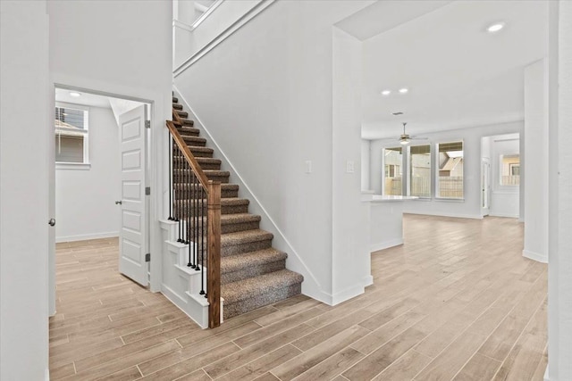 staircase featuring wood-type flooring and ceiling fan