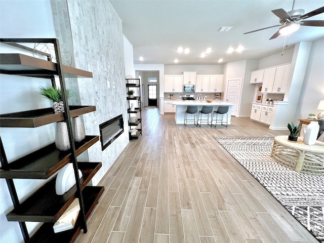 living room with light hardwood / wood-style floors, a tile fireplace, and ceiling fan