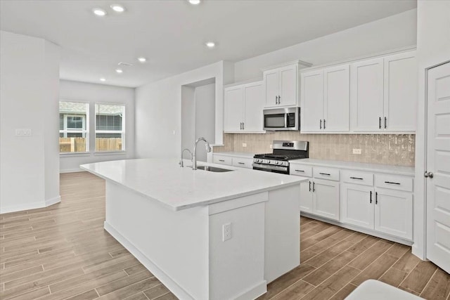 kitchen featuring white cabinetry, appliances with stainless steel finishes, sink, and a kitchen island with sink