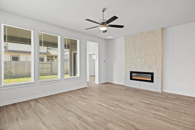 unfurnished living room featuring ceiling fan, a fireplace, and light hardwood / wood-style floors