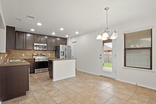 kitchen featuring appliances with stainless steel finishes, pendant lighting, sink, a center island, and light tile patterned floors