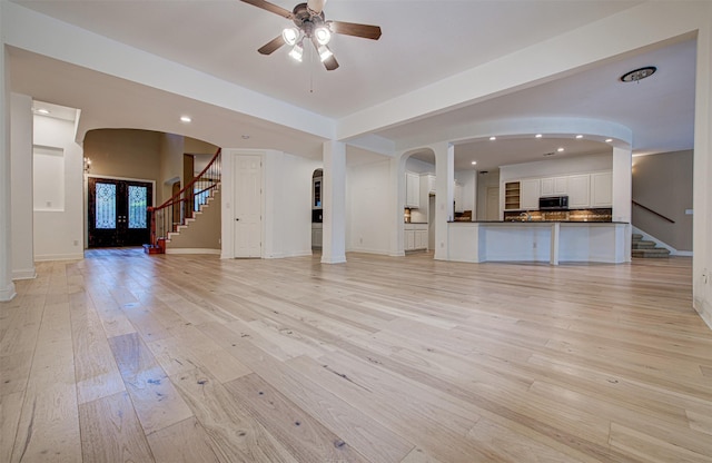 unfurnished living room with french doors, ceiling fan, and light hardwood / wood-style flooring