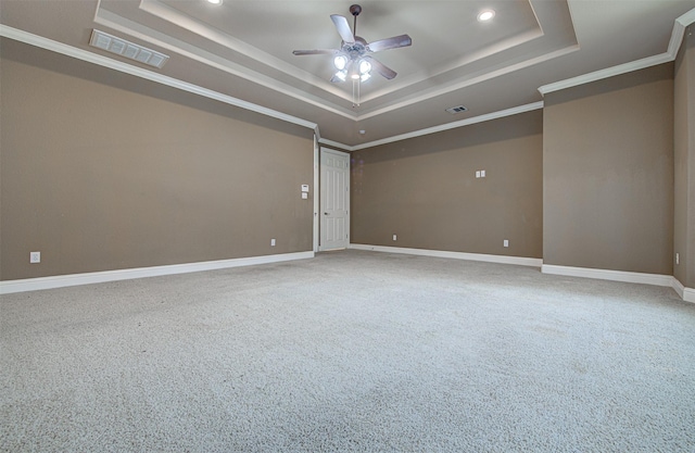 carpeted empty room featuring crown molding, ceiling fan, and a raised ceiling