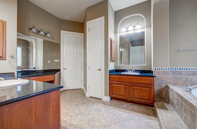 bathroom featuring tiled tub, vanity, and tile patterned flooring