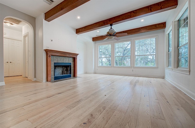 unfurnished living room with beamed ceiling, a tile fireplace, ceiling fan, and light hardwood / wood-style flooring