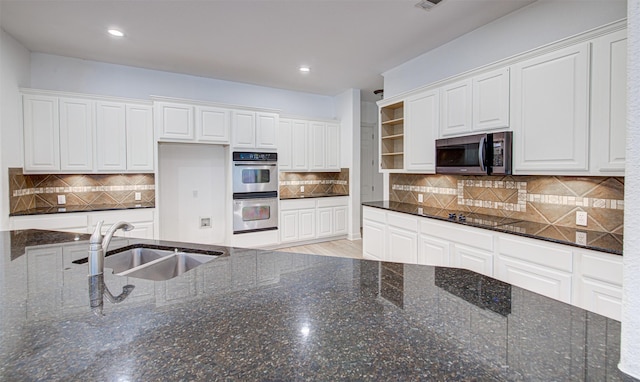 kitchen featuring stainless steel appliances, white cabinetry, sink, and dark stone counters