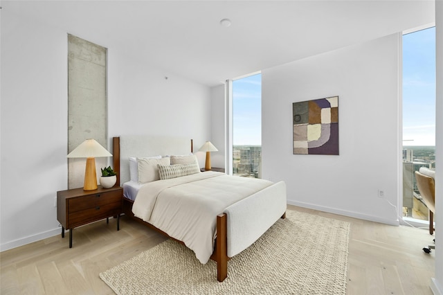 bedroom with floor to ceiling windows and light hardwood / wood-style floors