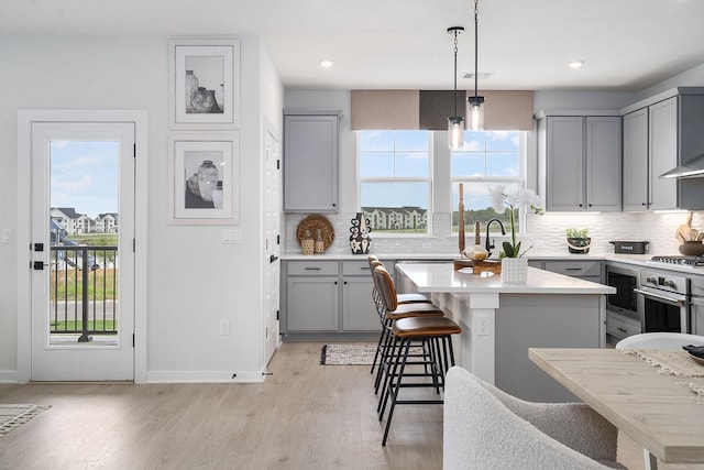 kitchen with gray cabinetry, stainless steel appliances, a center island, and a kitchen bar