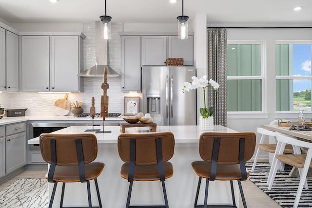 kitchen featuring backsplash, stainless steel appliances, hanging light fixtures, and gray cabinetry