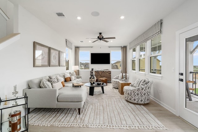 living room with plenty of natural light, ceiling fan, and light wood-type flooring