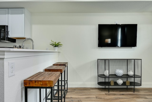 interior space featuring sink, light wood-type flooring, and white cabinets