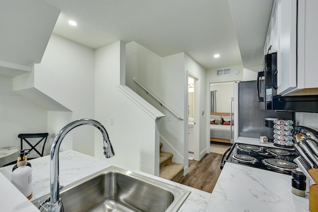 kitchen with sink, white cabinetry, electric range oven, dark hardwood / wood-style floors, and light stone countertops