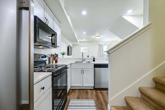 kitchen featuring a sink, black appliances, light countertops, white cabinetry, and dark wood-style flooring