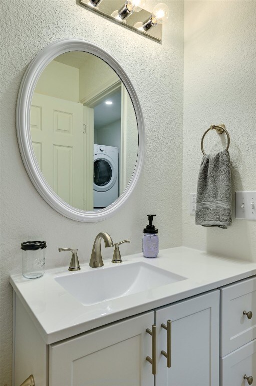 bathroom featuring washer / dryer, vanity, and a textured wall