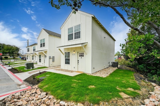 exterior space featuring a lawn, board and batten siding, and central AC